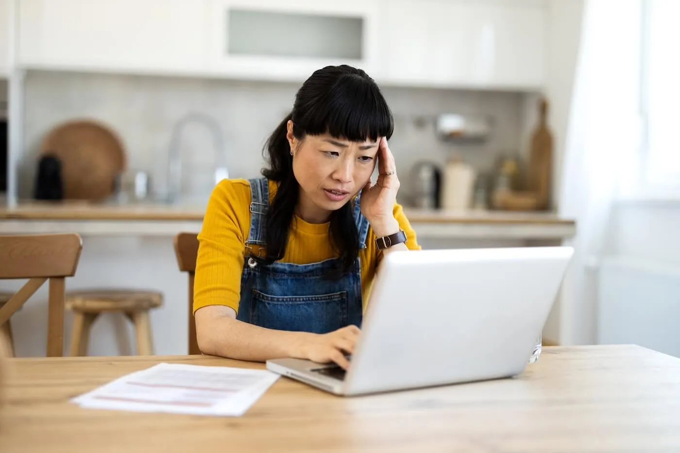 Concerned woman checking her credit score online in the kitchen